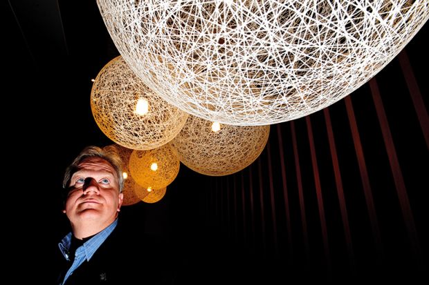 Nobel laureate Brian Schmidt looking up at lit up spheres
