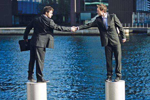 Businessmen shaking hands from pedestals in river