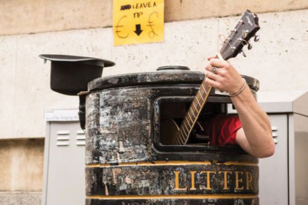 Busker playing guitar in litter bin