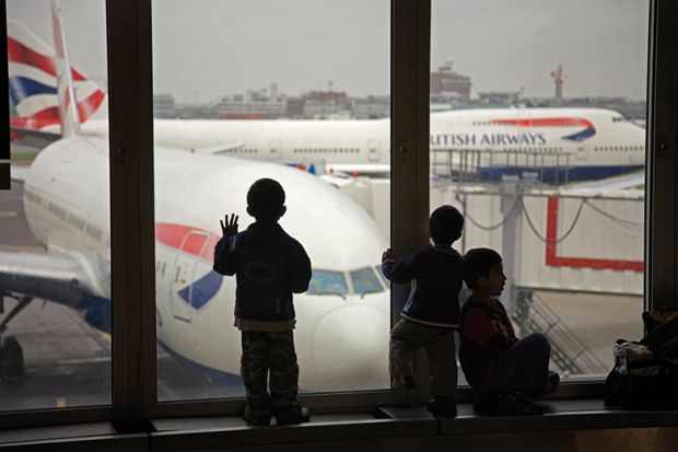 Children looking at British Airways planes out of an airport window. To illustrate the UK banning dependants. 