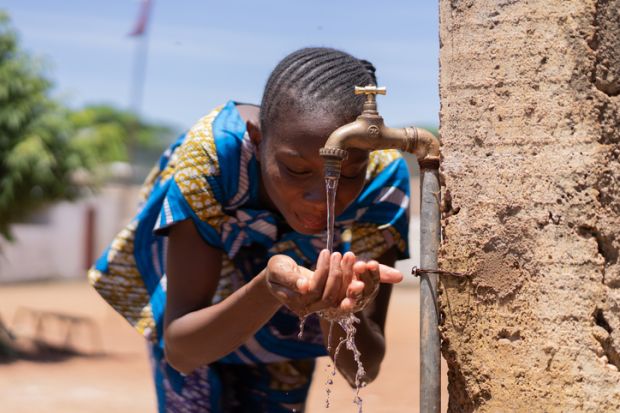 children drinking and playing with water in Bamako, Mali