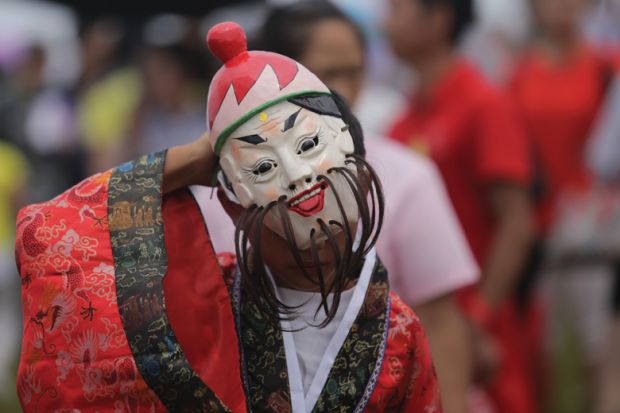 Chinese folk artist wearing mask performs
