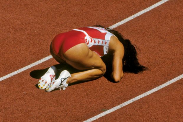 Competitive sprinter kneeling on race track