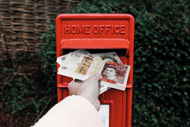 A hand stuffs banknotes into a post box marked ‘Home Office’