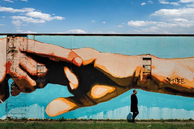 Man walking past mural of clasped hands