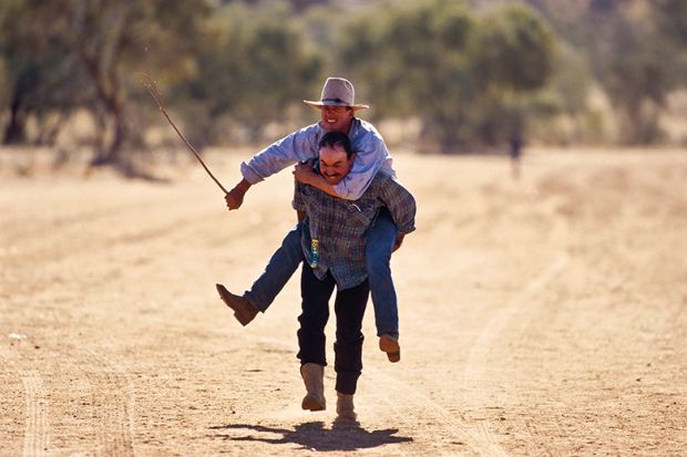 Cowboy carries friend on his back