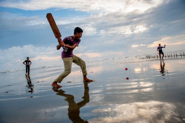 Boys play cricket on the beach