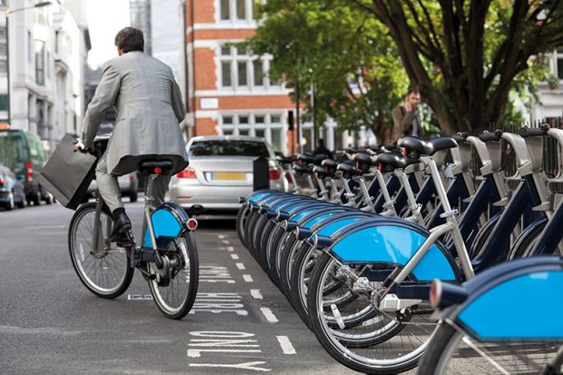 Man in suit rides Boris bike (Santander cycle) in London