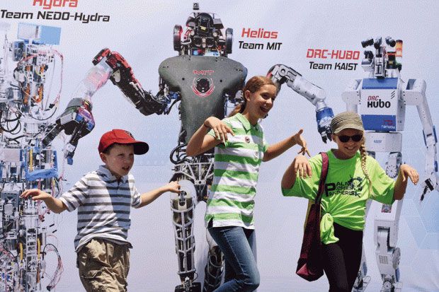 Children posing in front of picture of robots