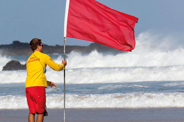 Man holding red flag on beach