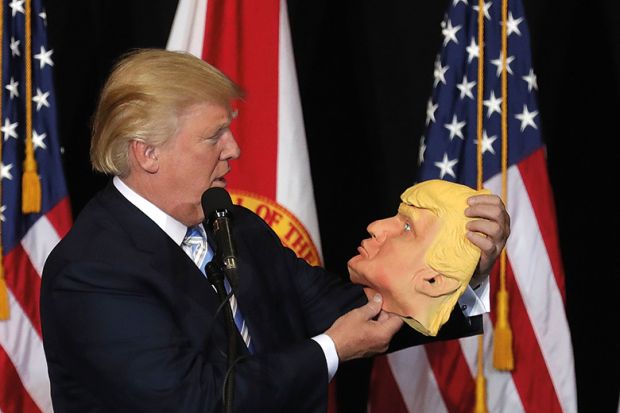 Donald Trump holding mask of his own face