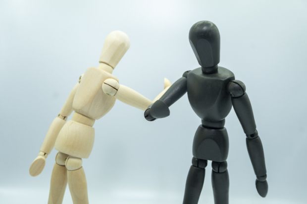 A black and a white wooden mannequin elbow bump illustrating EDI, equality diversity inclusion policy