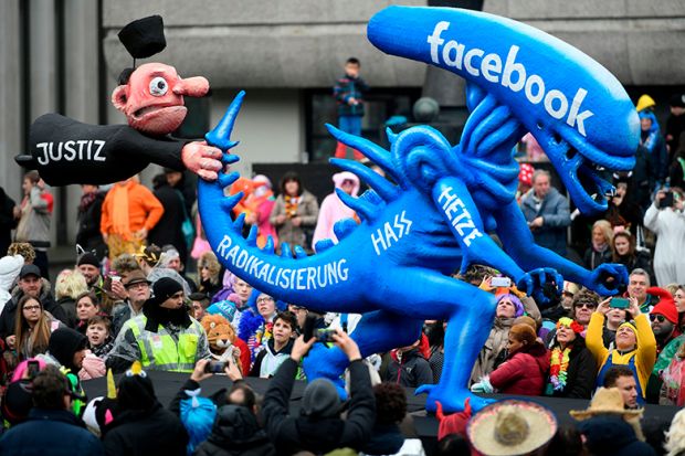 A carnival float depicting a judge holding the tail of an alien whereupon is written 'radicalisation, hate, rush, Facebook' in Germany 2020. To illustrate whether scholars on Facebook's oversight board are helping rule on moderation rows.