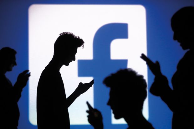 Silhouettes of people using smartphones in front of Facebook logo