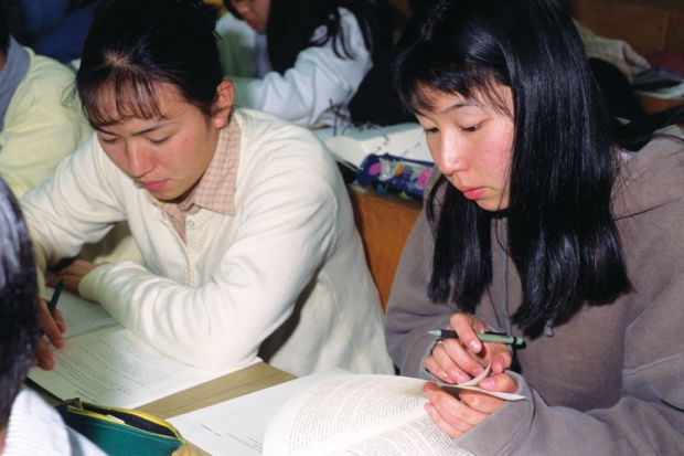 Female Japanese students reading textbooks