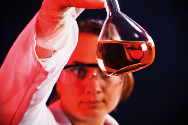 Female scientist examining flask of liquid