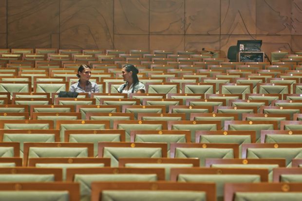 Female students chatting in empty lecture hall