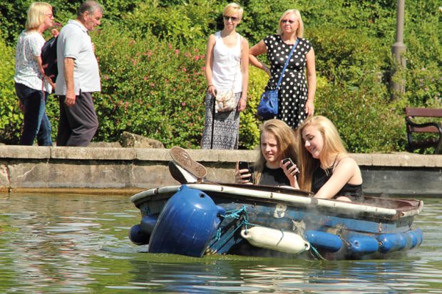 Female students using smartphones on boating lake