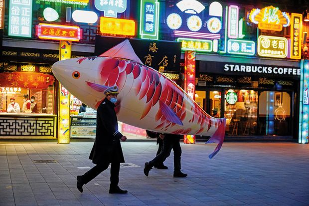 Security guards wearing face masks carry a giant balloon in the shape of a fish in Shanghai