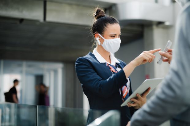 flight attendant talking to businessman on airport, wearing face mask