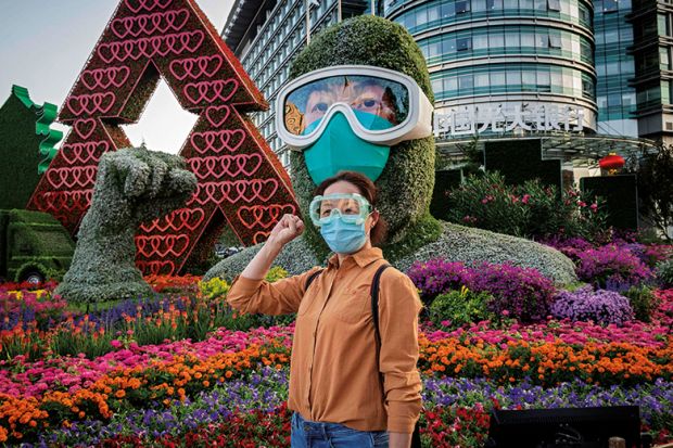 A woman poses in front of a flower display dedicated to healthcare workers during the Covid-19 pandemic
