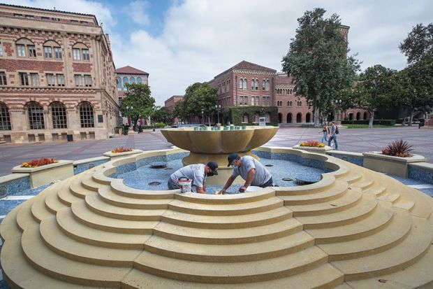 Men repair damaged tiles inside a fountain on the USC campus in Los Angeles