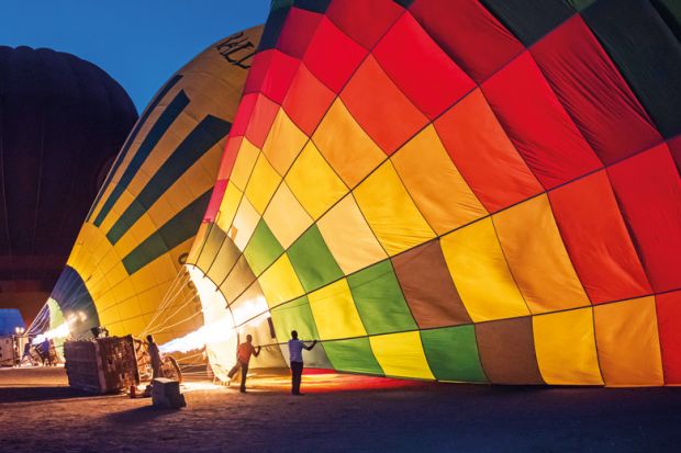 Gas burners filling hot air balloons at dawn