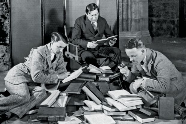Group of men reading pile of books