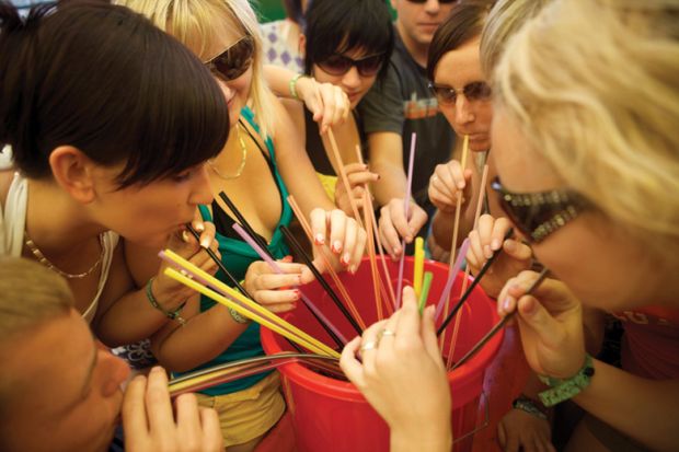 Group of women drinking through straws from bucket