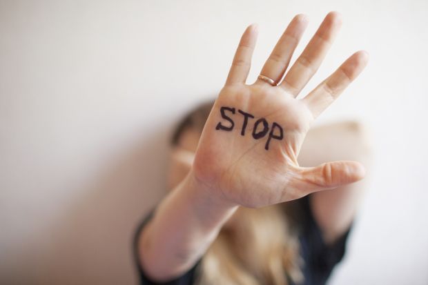 A woman with "stop" written on her palm, symbolising harassment