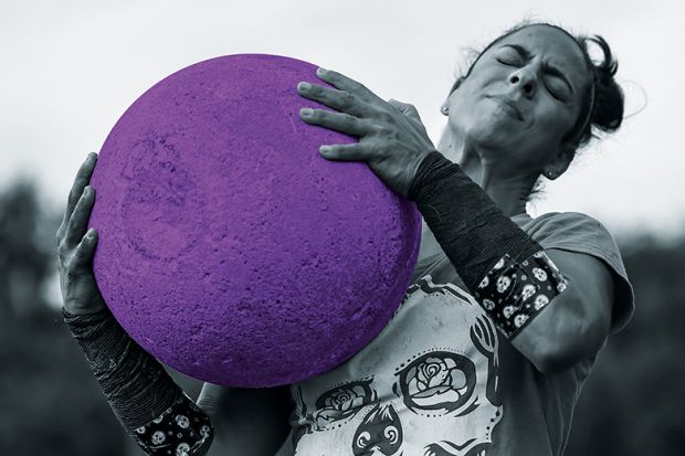 woman lifts heavy ball