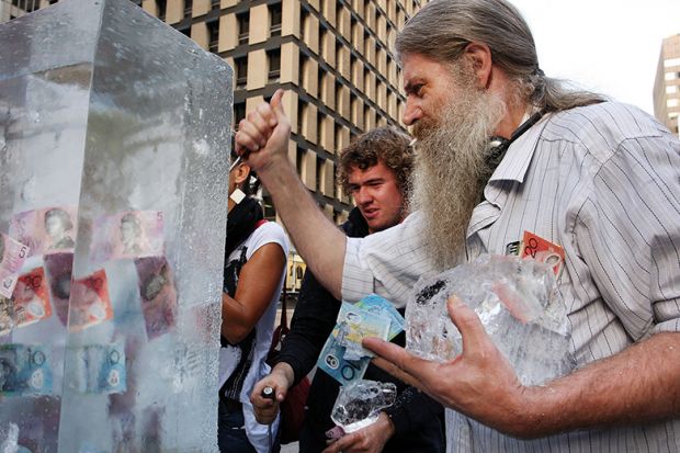 People chip at ice block to reach money frozen inside