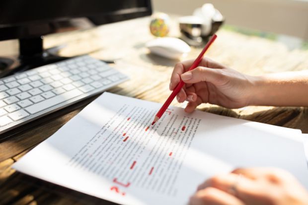 Person marking an error on a page with red marker