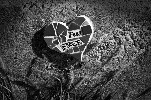 Heart-shaped mosaic reads “feel free” in New Orleans, after Katrina, illustrating a review of “Conflict Graffiti” by John Lennon