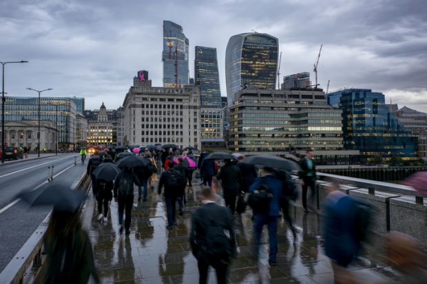 People cross a London bridge in the rain