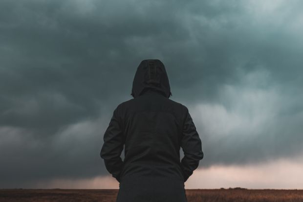 A person with their back to the camera looks at a big grey cloud