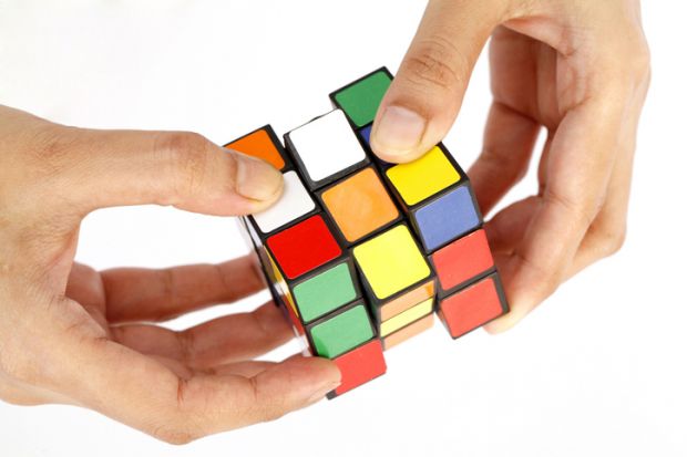 Hands trying to solve Rubix Cube as a way to show complexity in higher education funding