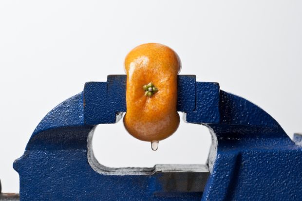 Orange being squeezed in a vice