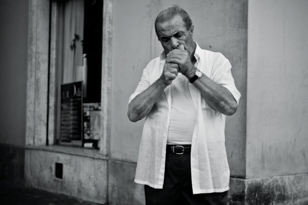 Italian man cupping hands to light cigarette