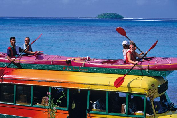 people sitting in kayaks on top of a bus