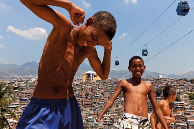 Children play near cable cars that cross over Complexo do Alemao in Rio de Janeiro, Brazil