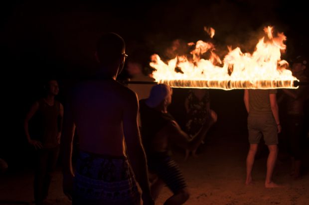 Koh Tao, Thailand - December 10, 2017 Young people partying and dancing limbo at fire show on the beach