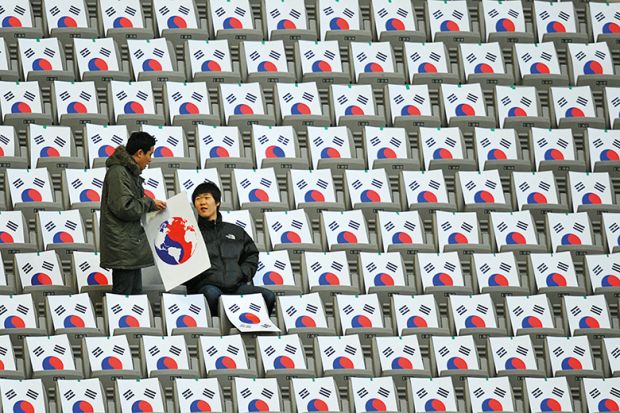 South Koreans sit in seats with the South Korean national flag at the Seoul World Cup Stadium in Seoul