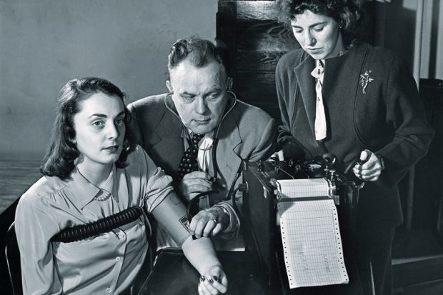 Two researchers conducting a lie detector test on a young woman