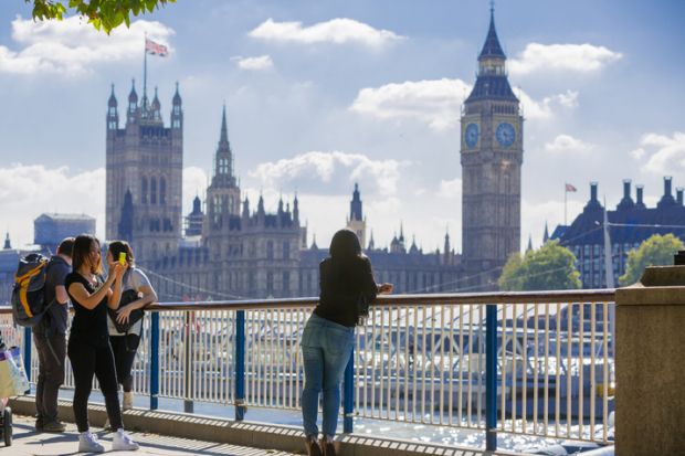 London, UK - September 10, 2015 Tourists talking and making a photos against of Houses of Parliament. View from the Thames embankment. London