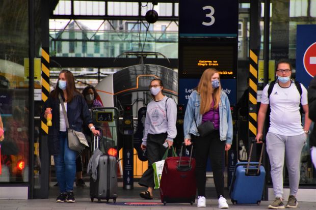 London, United Kingdom - August 17 2020 Passengers with protective face masks and luggage leaving King's Cross Station