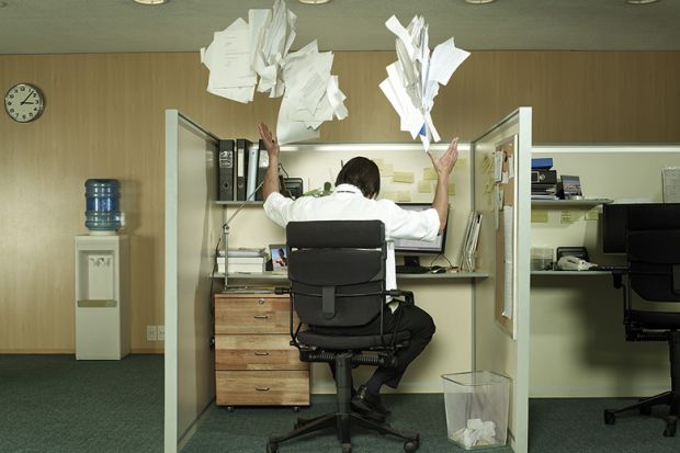 Man at desk throwing papers in the air