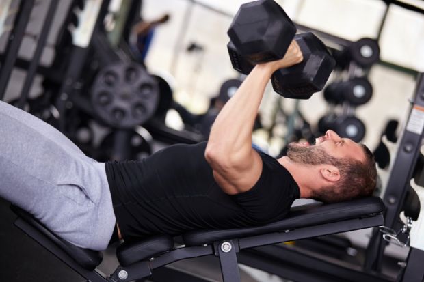 Man bench pressing with dumbbells
