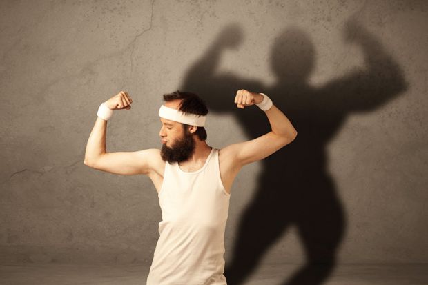 Man flexing muscles with shadow on wall