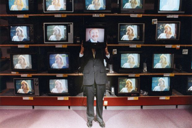 Man holding television in front of face in television shop